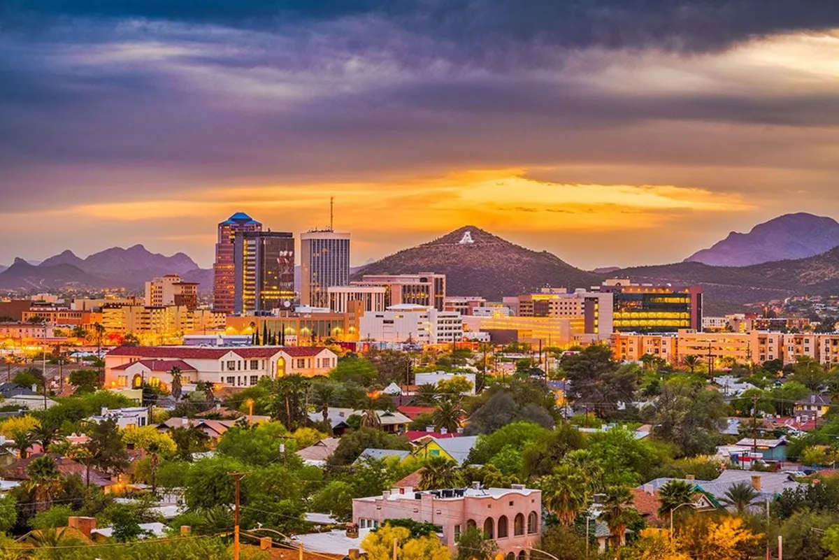 A sweeping view of the downtown skyline with a stunning mountain backdrop under a vibrant sunset sky. The cityscape hints at nearby attractions, dining, and nightlife options, all within reach of the home.