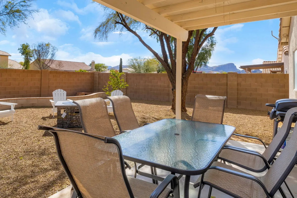 A glass dining table set on a welcoming patio with comfortable chairs and a scenic desert landscape beyond. The outdoor setting is inviting for al fresco dining, BBQ nights, or morning coffee under the open sky.