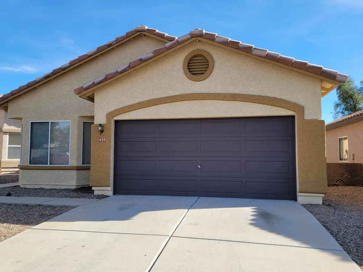 The exterior of a welcoming home featuring a garage door, distinctive roof design, and a front entryway. The yard area hints at spaces suitable for outdoor family activities, such as barbecues or children's games.